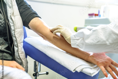 Фотография Details of a nurse hand looking for vein in arm of patient girl drawing blood sample for blood test in blood testing laboratory