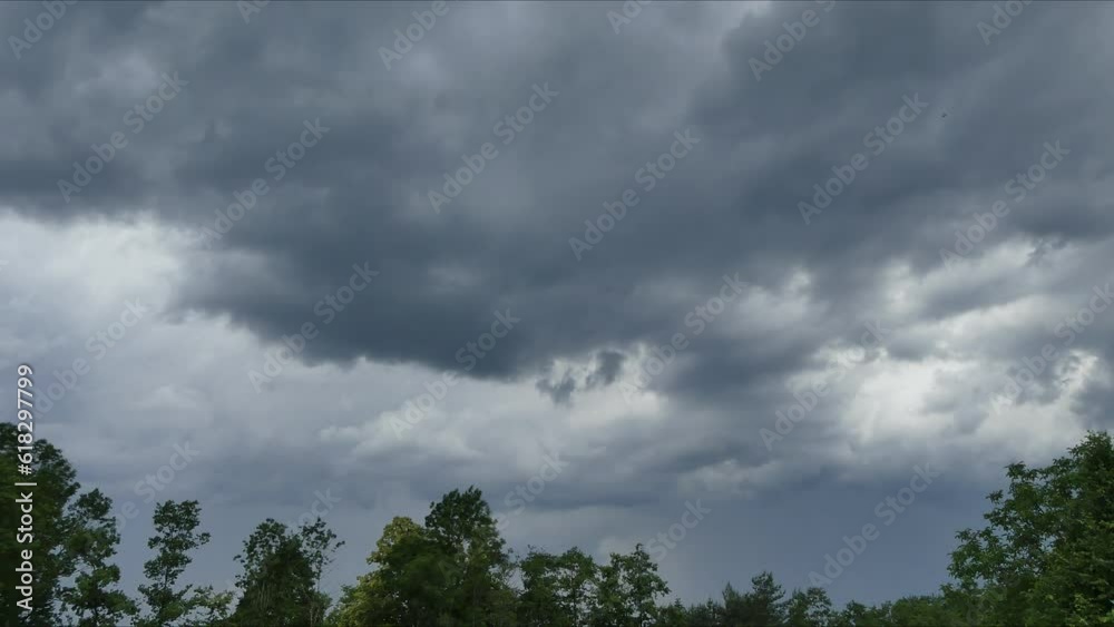 Time lapse - fast moving clouds over trees in summer. Variable weather with rainy dark clouds, rainfall and clearing up with blue sky revealing. Topics: weather, meteorology, climate, cloudscape Time lapse - fast moving clouds over trees in summer. Variable weather with rainy dark clouds, rainfall and clearing up with blue sky revealing. Topics: weather, meteorology, climate, cloudscape