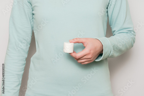Plastic jar (container) in a woman's hands. Cosmetic product.