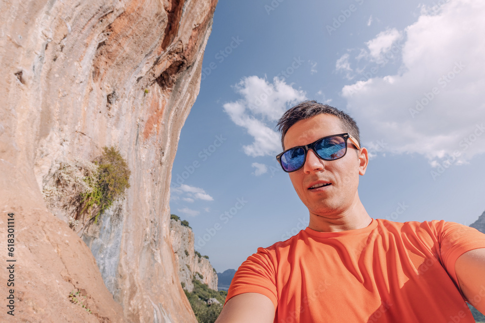Happy hiker or climber man taking selfie photo on a trail in mountains with famous Geyikbayiri rocks and canyon in the background