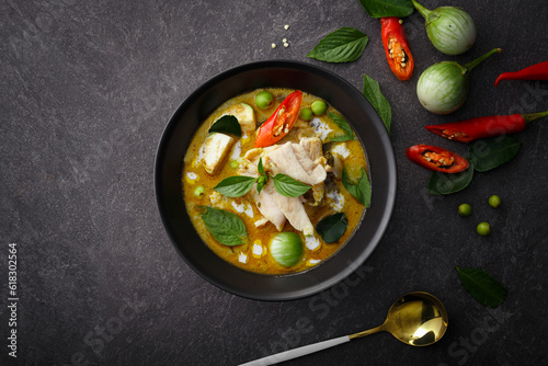 Exquisite Thai Cuisine: Green Curry Chicken, Infused with Aromatic Chili Paste and Creamy Sauce, Presented in a Black Bowl on a Textured Background