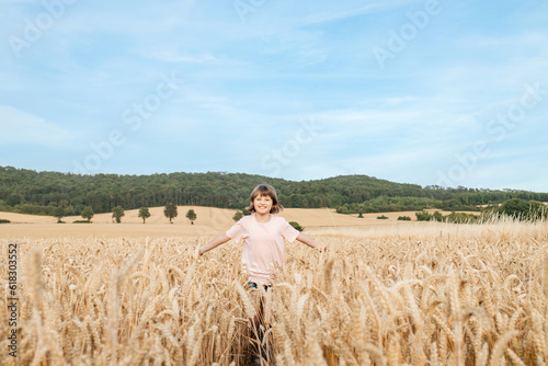 A happy school-age girl walks through a field of mature spikelets. Country life. summer holiday vacation. Vacation concept. © Elena Medoks