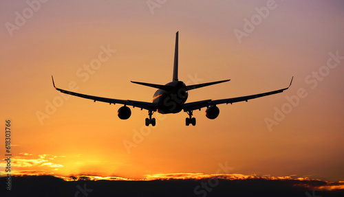 The silhouette of a passenger airplane flying in sunset