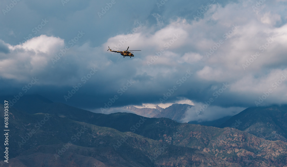 Military helicopter in the sky over the mountains in cloudy weather