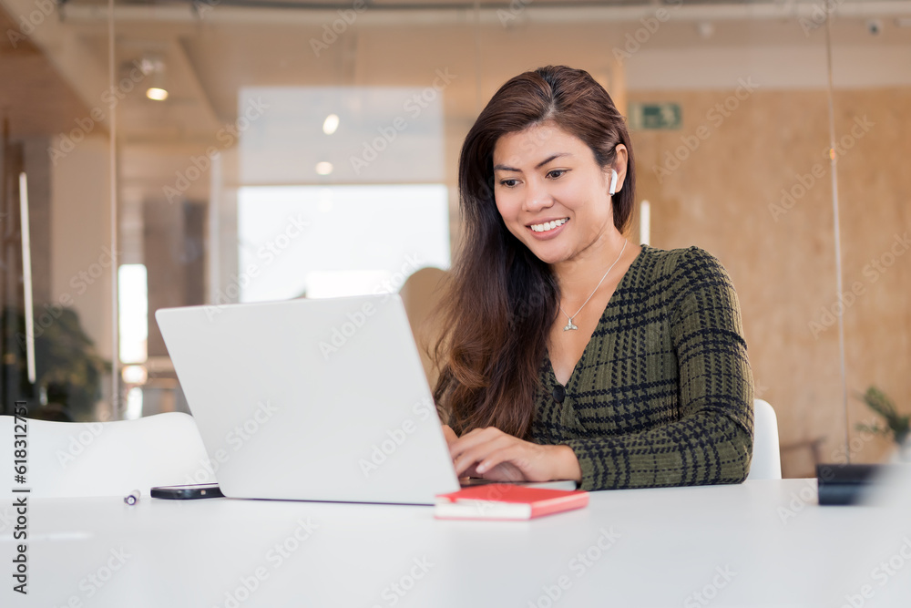 Smiling woman working on laptop in office Smiling woman working on laptop in office
