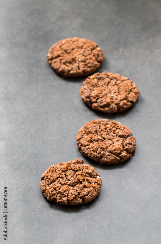 Chocolate cookies with oatmeal, chocolate chips and hazelnuts. Dark grey background. Chocolate cookies with oatmeal, chocolate chips and hazelnuts. Dark grey background.