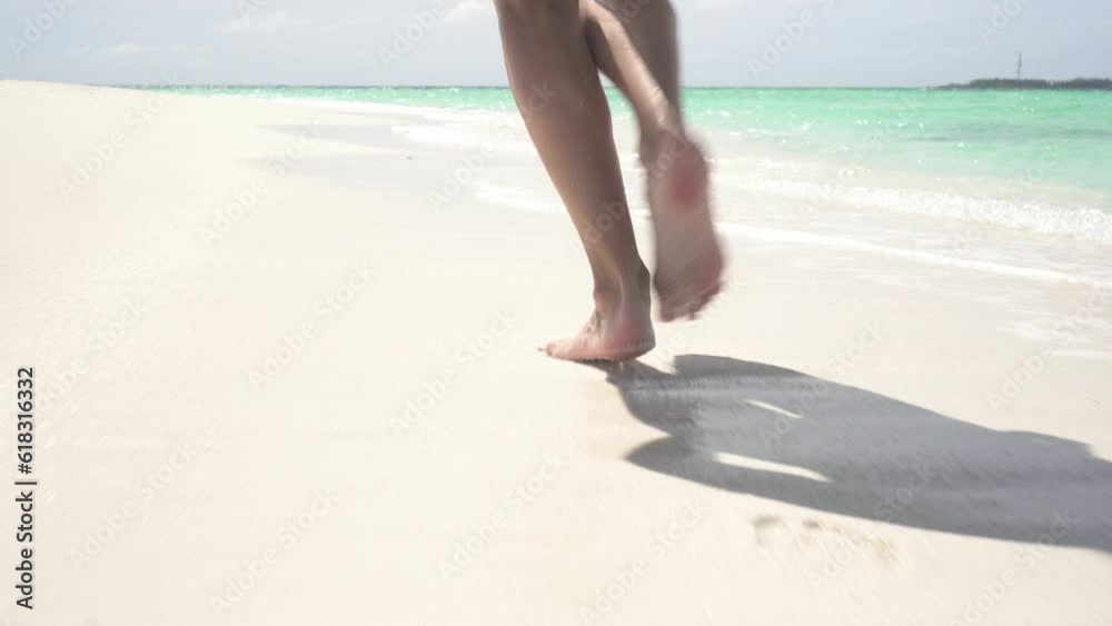 Young happy woman in a swimsuit runs along the sea sandy beach. Slim legs and feet close-up Young happy woman in a swimsuit runs along the sea sandy beach. Slim legs and feet close-up
