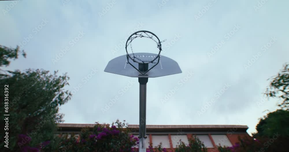 Static shot of basketball hoop with chain swaying after a precise shot. Practice penalty shots. Competition breakaway steel rim, heavy duty or recreation flex goal, and the fixed rim for street Static shot of basketball hoop with chain swaying after a precise shot. Practice penalty shots. Competition breakaway steel rim, heavy duty or recreation flex goal, and the fixed rim for street