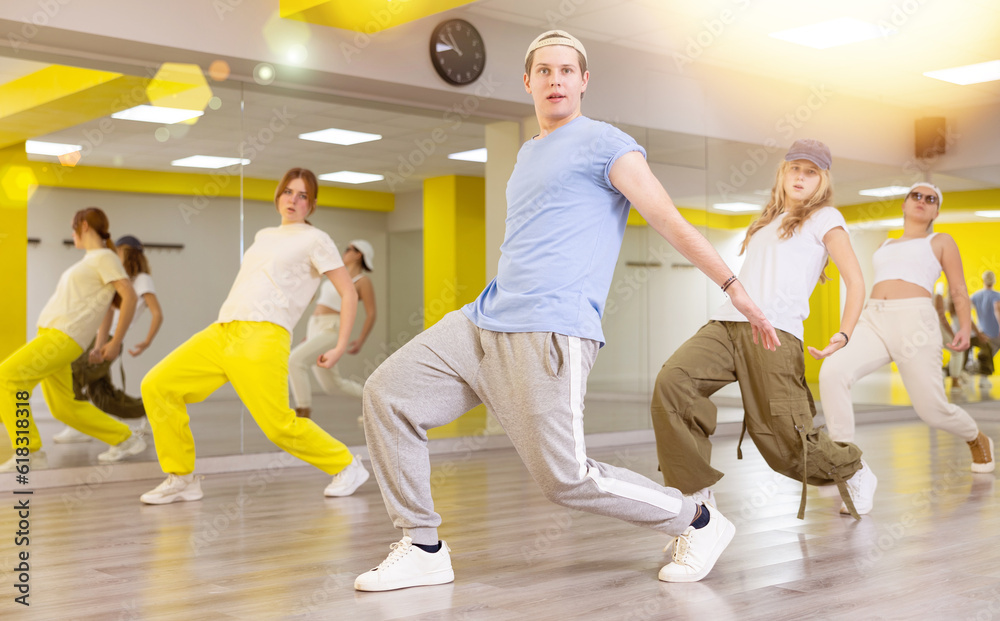 Teenage dancers, young people practicing modern dance styles together in spacious studio with mirrors