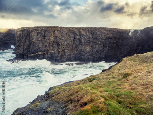 Rough stone coastline, Cliffs of Kilkee county Clare, Ireland. Wild Irish nature landscape. Popular travel area with stunning nature scenery. Dramatic sky and powerful ocean waves.