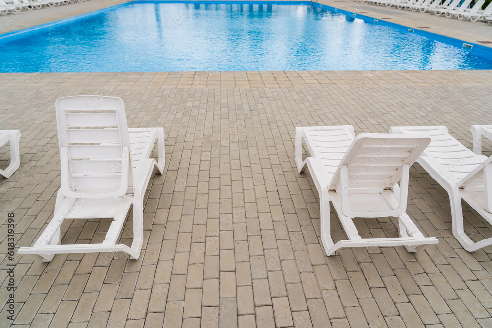 Fototapeta premium Empty sun loungers in the resort area by the pool. Background with copy space for text