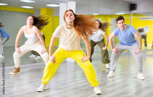Flexible and energetic male and female teenage dancers having fun during dance lesson together in spacious hall