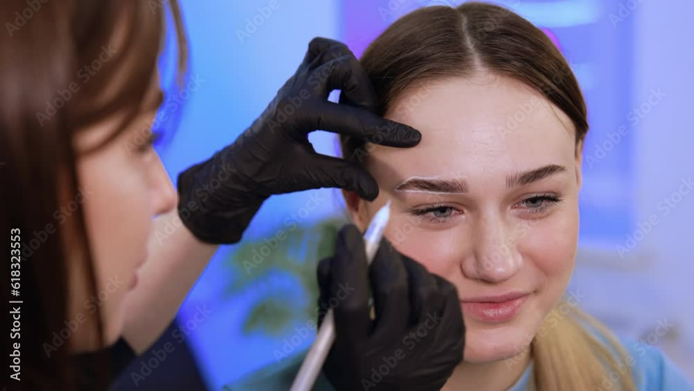 Salon brow master applying white marks around girl's eyebrows. Preparatory process for eyebrow make up. Close up. Salon brow master applying white marks around girl's eyebrows. Preparatory process for eyebrow make up. Close up.