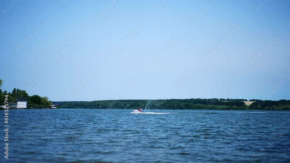 People riding jet ski water bike on the river on sunny day. Two water bikers slowly approaching the waterfront. People riding jet ski water bike on the river on sunny day. Two water bikers slowly approaching the waterfront.