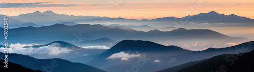 Mountain ridges covered with a forest shrouded in dawn- kissed clouds