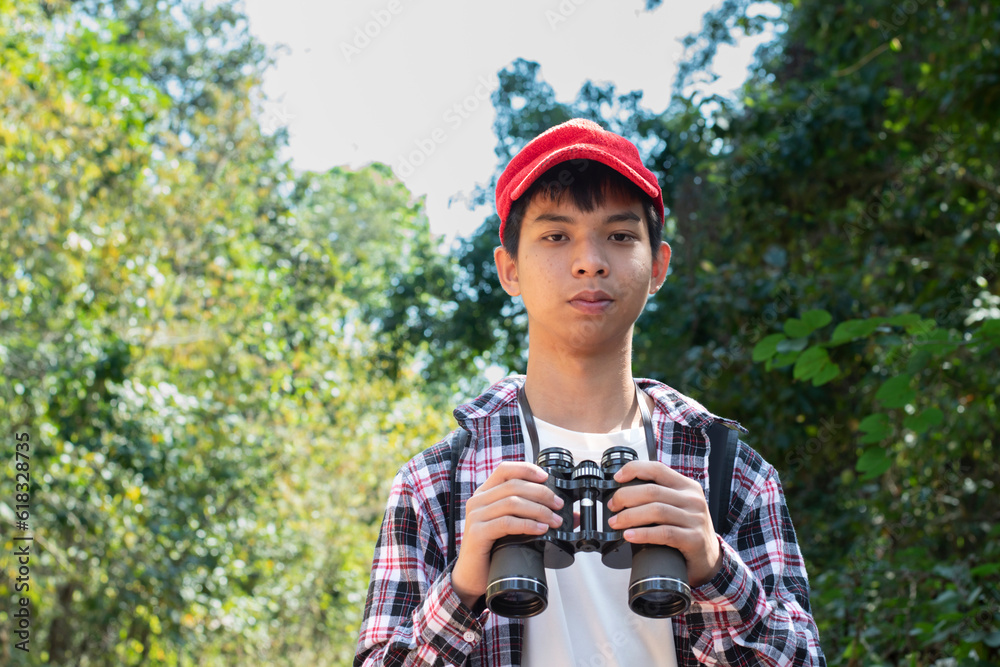 Asian boys are using binoculars to do the birds' watching in tropical forest during summer camp, idea for learning creatures and wildlife animals and insects outside the classroom. Asian boys are using binoculars to do the birds' watching in tropical forest during summer camp, idea for learning creatures and wildlife animals and insects outside the classroom.