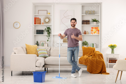 Spring cleaning. Man with mop washing floor at home