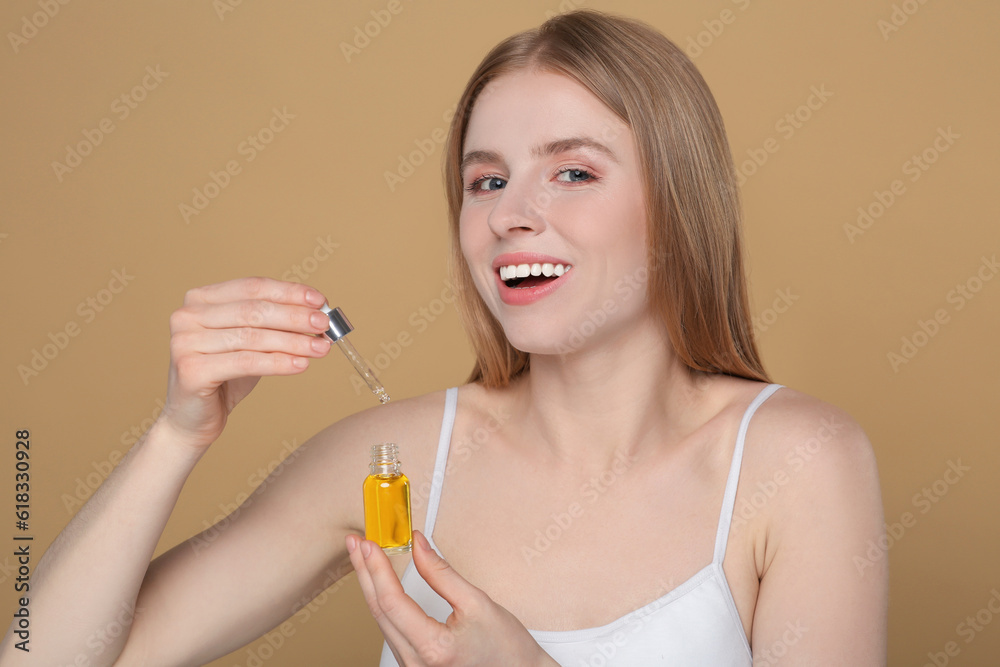 Beautiful young woman with bottle of essential oil on brown background Beautiful young woman with bottle of essential oil on brown background