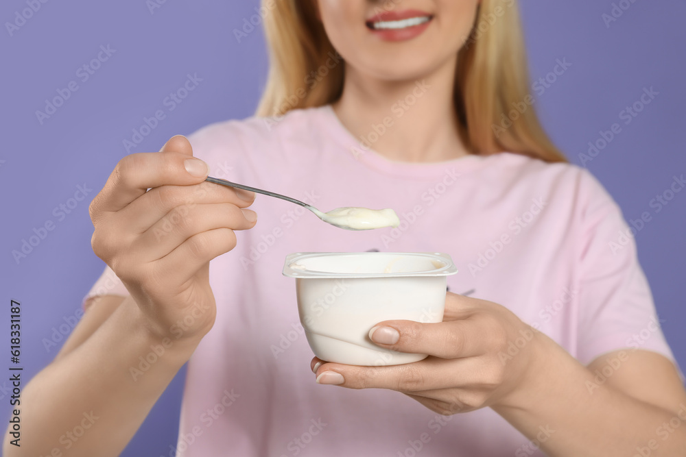 Closeup of woman with tasty yogurt on violet background Closeup of woman with tasty yogurt on violet background