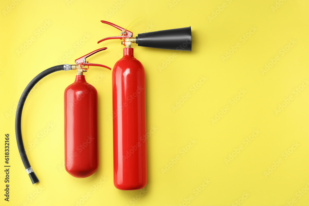 Obraz premium Fire extinguishers on yellow background, flat lay. Space for text