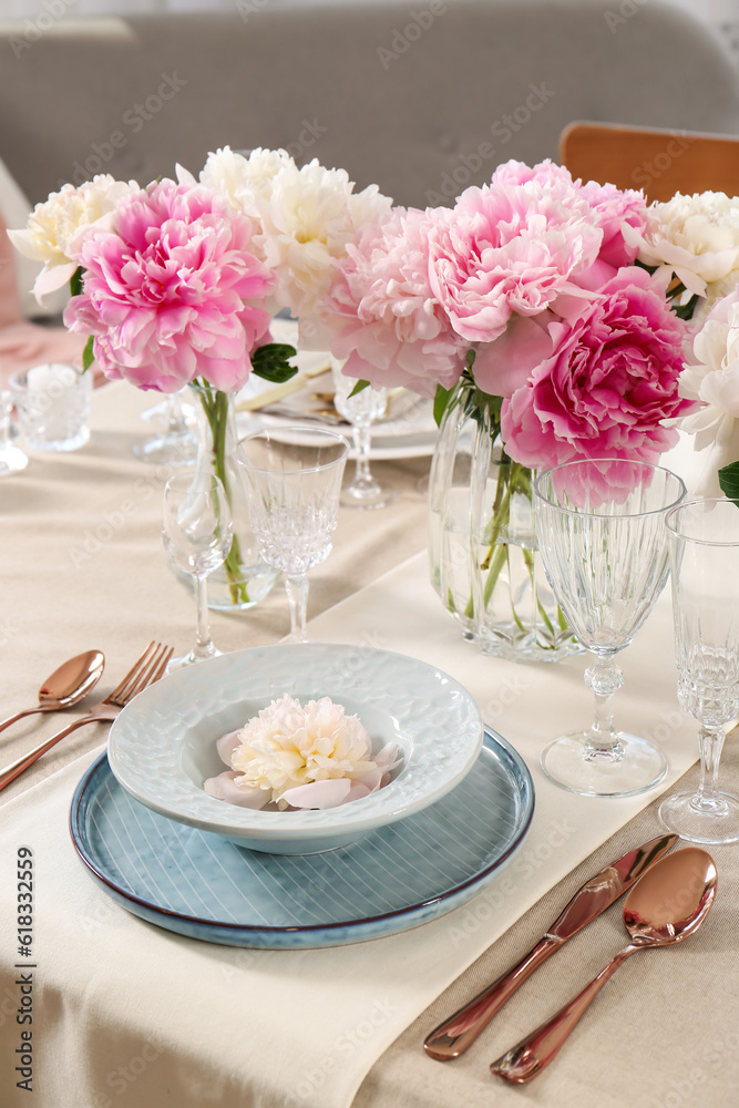 Stylish table setting with beautiful peonies and golden cutlery indoors