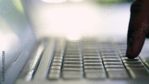 close up of fingers typing on silver laptop keyboard selective focus
