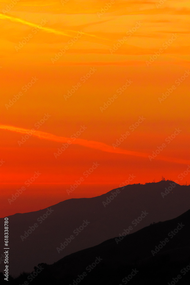 Sunset or sun rise behind trees and mountains