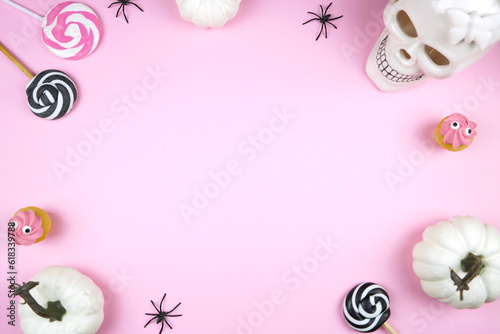 Pink Halloween framed border background backdrop. Trick or treat party styled with white skull, pumpkins, black spiders, and spooky cupcakes. Negative copy space.