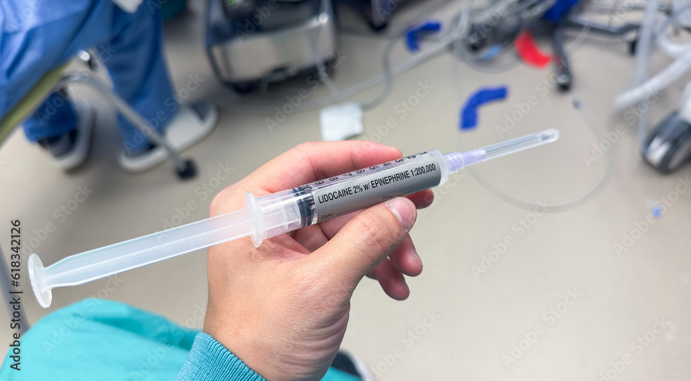 hand holds a syringe amidst IV drips and medications, symbolizing medical care, treatment, and the use of drugs in a hospital setting hand holds a syringe amidst IV drips and medications, symbolizing medical care, treatment, and the use of drugs in a hospital setting