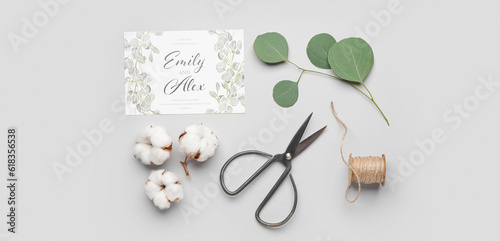 Composition with beautiful wedding invitation, scissors and cotton flowers on light background