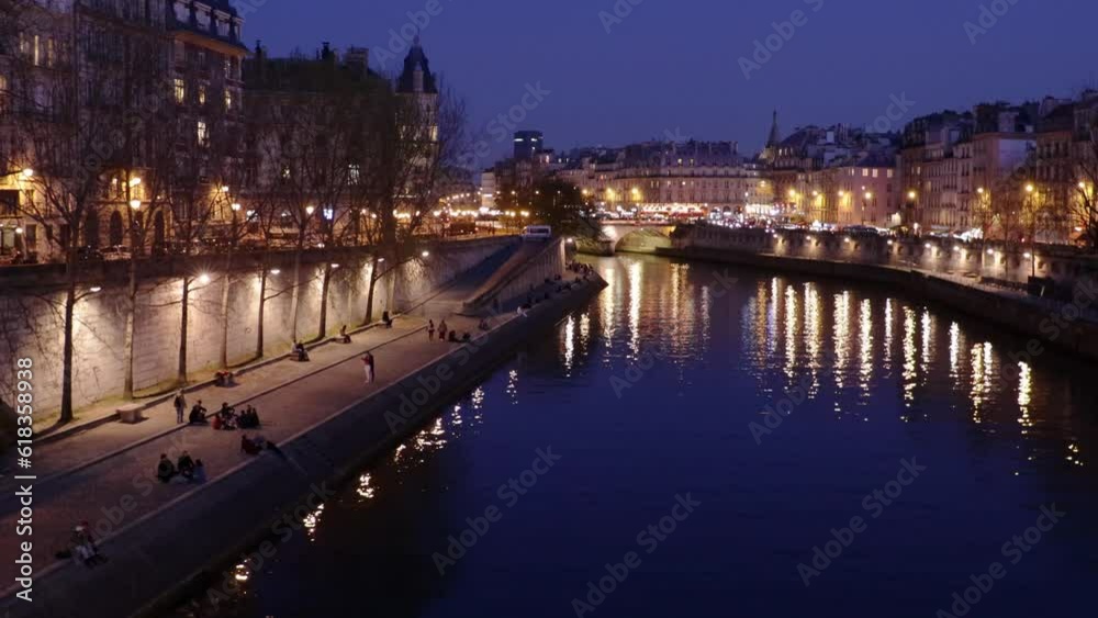 Paris famous Quais de Seine river bank by night with lights and people, wide panning shot Paris famous Quais de Seine river bank by night with lights and people, wide panning shot