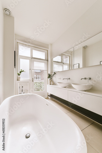 a bathroom with a large bathtub in the middle and two sinks on the other side  there is a window to the right