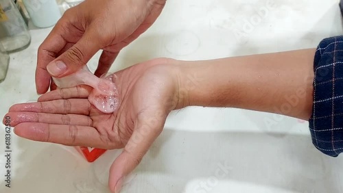 human hand is pouring red colored handsoap with pump bottle. healthy and clean living concept