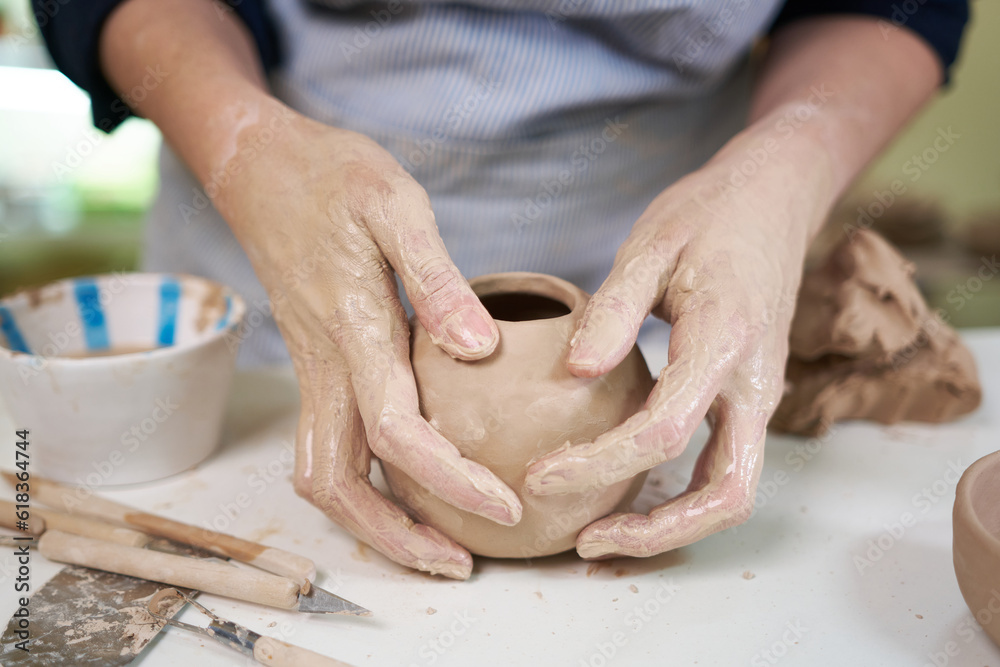 woman forming clay pot shape by hands, closeup in artistic studio