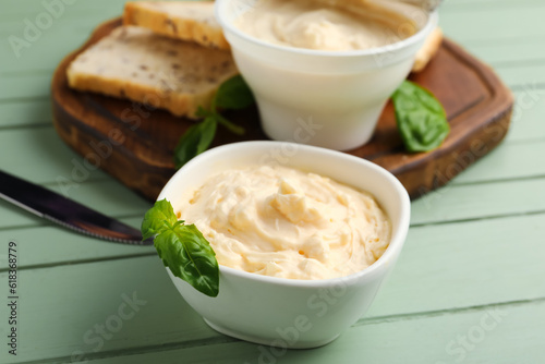 Bowl with tasty cream cheese on green wooden background