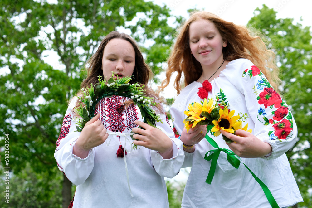 Ivana Kupala summer two girls friends put on heads. beautiful wreaths with numerous flowers Ukrainian folk dressing joy friend love beauty folk customs nature sunny strong wind