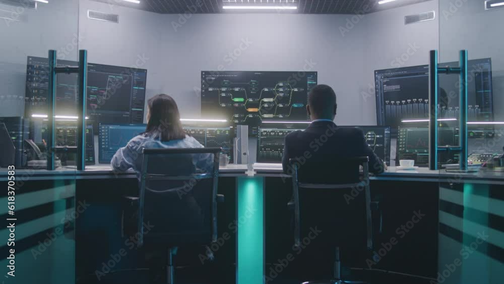 Software programmers work on computers. IT technical specialist enters modern monitoring control room, works with data server, real-time analysis charts and blockchain network on big digital screens.