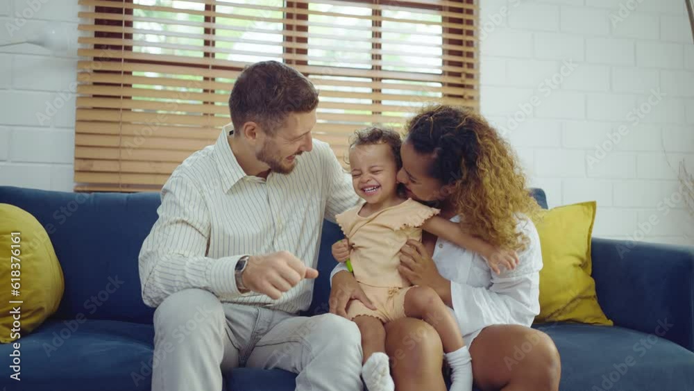 Happy cheerful parents having fun with cute daughter and hugging on sofa together, Enjoying family lifestyle at home concept. Happy cheerful parents having fun with cute daughter and hugging on sofa together, Enjoying family lifestyle at home concept.
