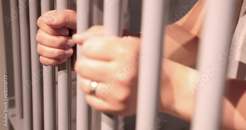 A person behind bars on a jail cell incarcerated