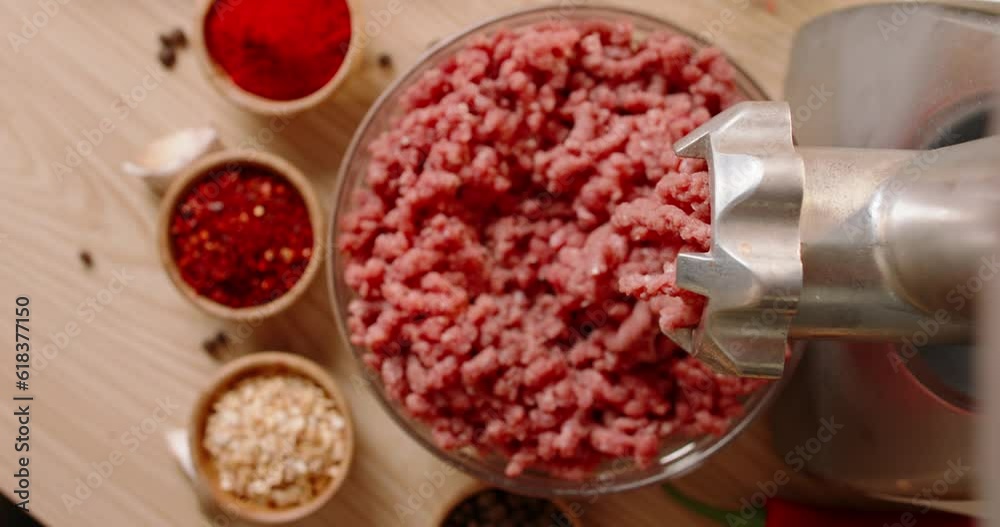 Cooking minced meat in grinder on wooden table with aesthetically arranged spices for burger. Top view slow motion Advertising. Grinding meat for stuffing, nature products, clean food ingredient Cooking minced meat in grinder on wooden table with aesthetically arranged spices for burger. Top view slow motion Advertising. Grinding meat for stuffing, nature products, clean food ingredient