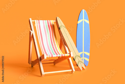 Photography Composition with mini surfboards and deckchair on orange background
