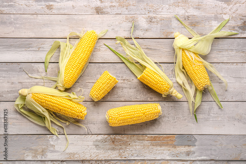 Fotografie Freshly harvested yellow corn cobs with husks on rustic wooden background, healt