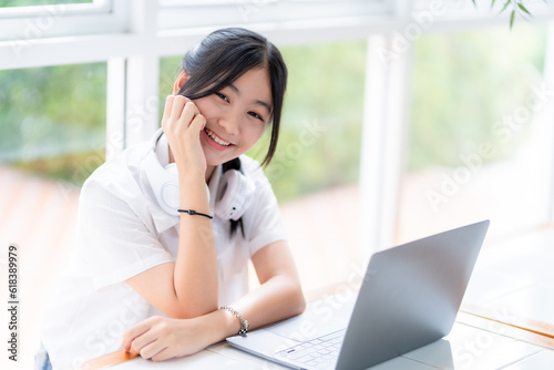 Happy of cute smiles Asian of attractive young Cute girl little wearing headphones using laptop computer working from at the cafe.Online education, elearning concept.