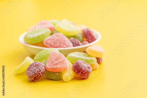 Quadro em tela Mix of fruity jelly candy in bowl on yellow background.