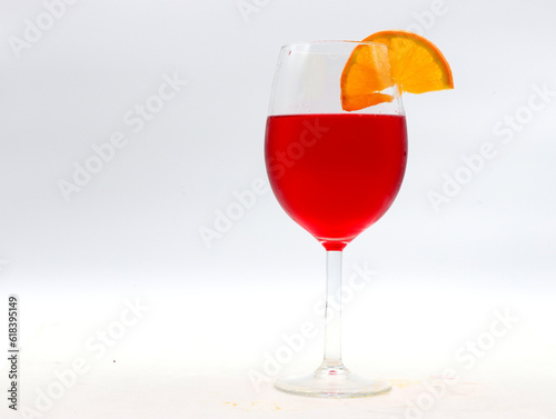 close-up of a goblet with red aperitif and orange slice on a white background