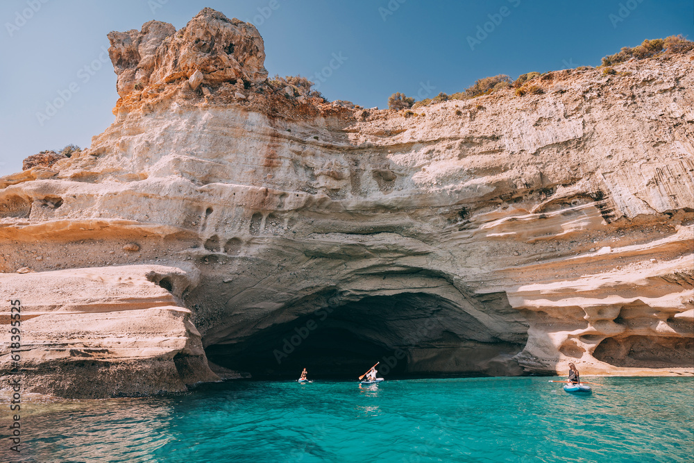 Group of sup boarders enters huge limestone cave on a sea coast