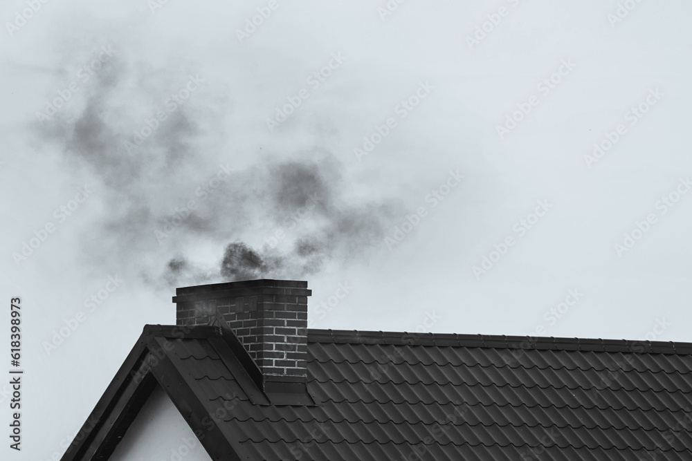 Foto de Black smoke comes out of a modern house chimney. The concept of