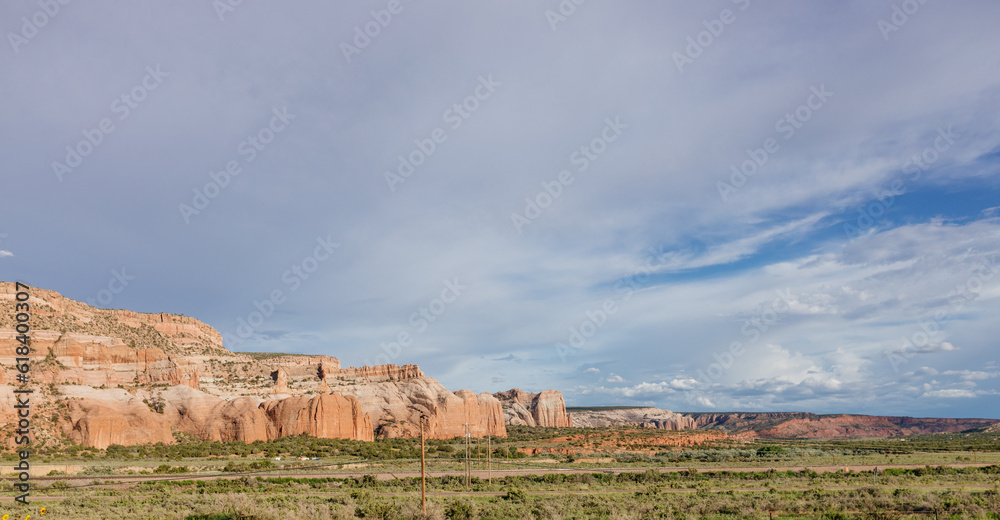 Beautiful summer landscape with highway among rocky mountains and dark blue sky with fluffy clouds on a summer day at sunset. American Roadscape with red canyons in New Mexico near Albuquerque, USA