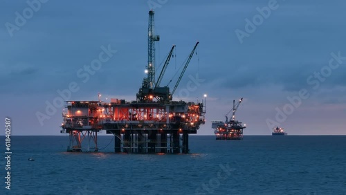 Beautiful aerial view of the offshore oil drilling rig, remaining afloat on the open ocean and illuminated ships, floating aside. Oil and gas extraction. High quality 4k footage photo