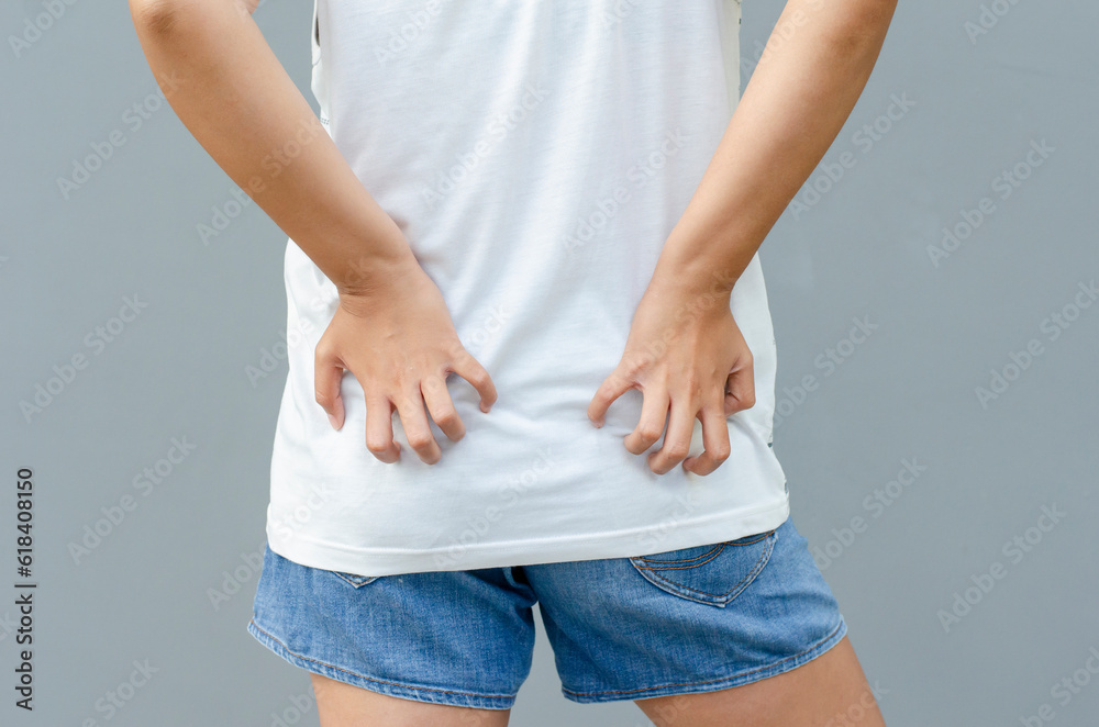 young asian woman scratching itch with hand on buttock area, health